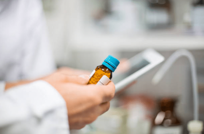 Pharmacien qui tient un flacon de granules homéopathiques dans sa main
